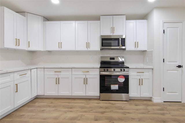 kitchen featuring tasteful backsplash, white cabinetry, stainless steel appliances, and light hardwood / wood-style floors