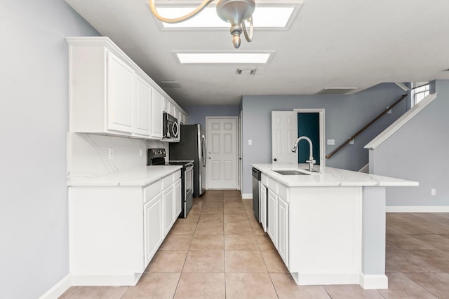 kitchen featuring sink, light tile patterned floors, light stone counters, white cabinetry, and stainless steel appliances