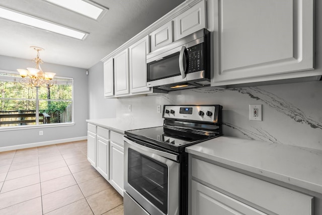 kitchen with white cabinets, light tile patterned floors, stainless steel appliances, and a notable chandelier