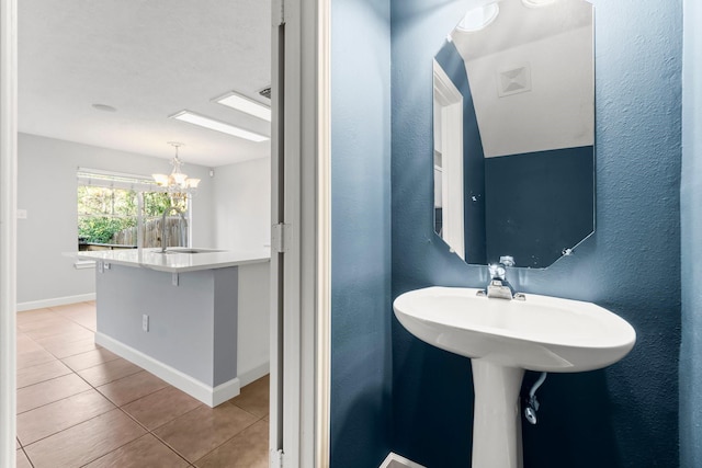 bathroom featuring tile patterned flooring, a chandelier, and sink