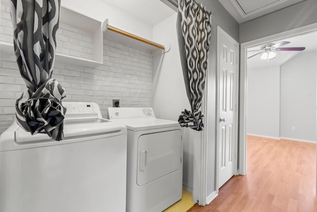 clothes washing area featuring light hardwood / wood-style floors, washer and clothes dryer, and ceiling fan