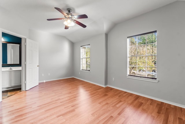 unfurnished bedroom featuring ensuite bathroom, sink, vaulted ceiling, ceiling fan, and light hardwood / wood-style floors