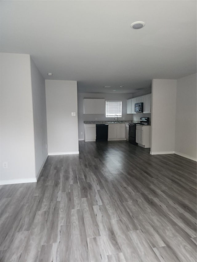 unfurnished living room featuring sink and light hardwood / wood-style floors