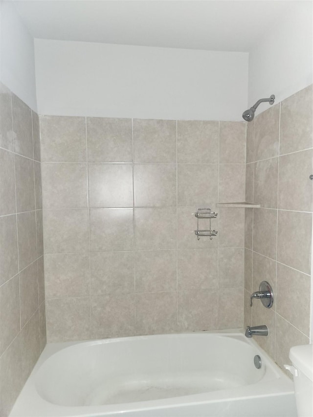 bathroom featuring tiled shower / bath combo and toilet