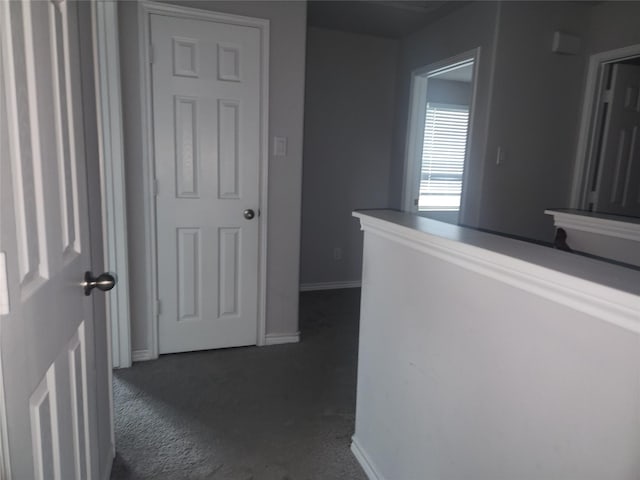 hall with dark colored carpet