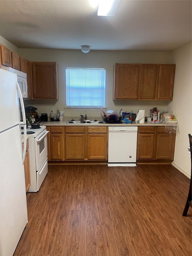 kitchen featuring sink, dark wood-type flooring, and white appliances