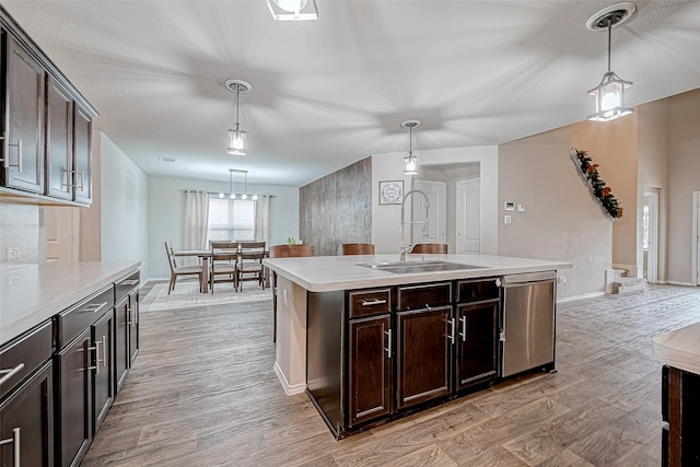 kitchen featuring dark brown cabinetry, sink, an island with sink, and stainless steel dishwasher