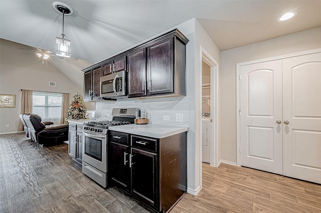 kitchen featuring dark brown cabinetry, stainless steel appliances, light hardwood / wood-style flooring, vaulted ceiling, and washer / dryer