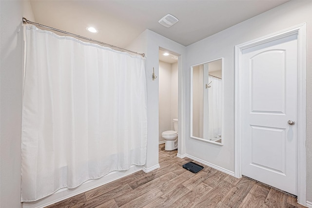 bathroom featuring hardwood / wood-style floors, shower / tub combo, and toilet