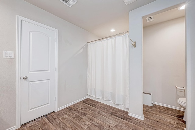 bathroom featuring hardwood / wood-style floors, shower / bath combo, and toilet