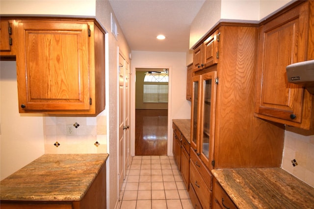 kitchen with decorative backsplash, light tile patterned flooring, and dark stone countertops