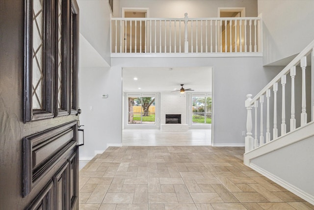 foyer entrance with a large fireplace and ceiling fan