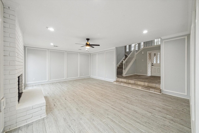 unfurnished living room featuring a brick fireplace, light hardwood / wood-style flooring, ceiling fan, and crown molding