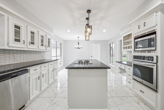 kitchen with white cabinetry, a center island, stainless steel appliances, tasteful backsplash, and decorative light fixtures