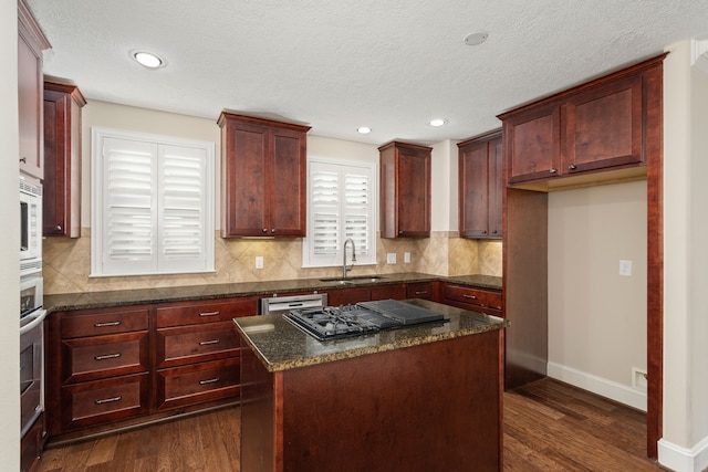 kitchen featuring a center island, dark hardwood / wood-style floors, dark stone counters, and sink