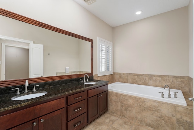 bathroom featuring vanity and tiled bath