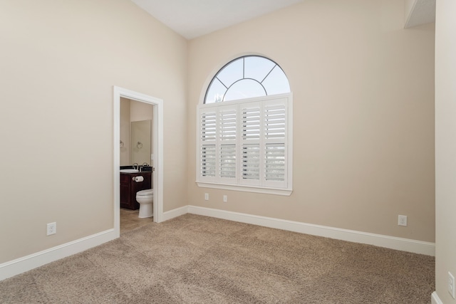 unfurnished bedroom featuring ensuite bath and light carpet