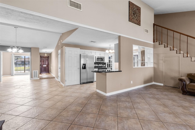 kitchen featuring appliances with stainless steel finishes, light tile patterned floors, decorative light fixtures, a notable chandelier, and white cabinets