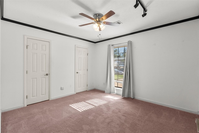 unfurnished bedroom with light carpet, track lighting, ceiling fan, and crown molding