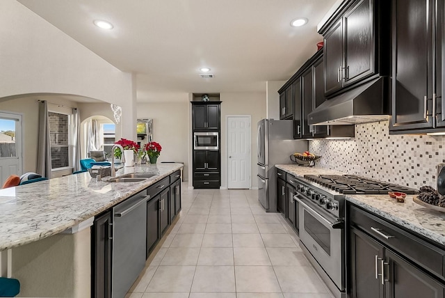 kitchen featuring backsplash, light stone counters, stainless steel appliances, sink, and light tile patterned floors