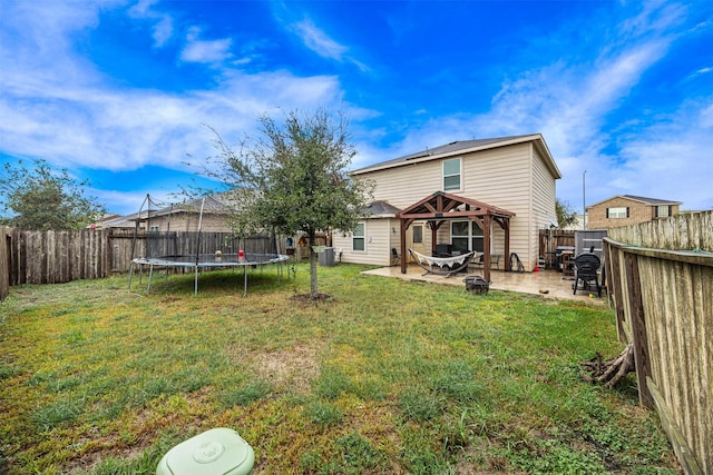 back of house with a gazebo, a trampoline, a patio area, and a lawn