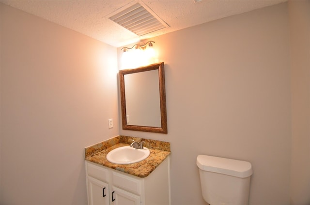 bathroom featuring vanity, a textured ceiling, and toilet