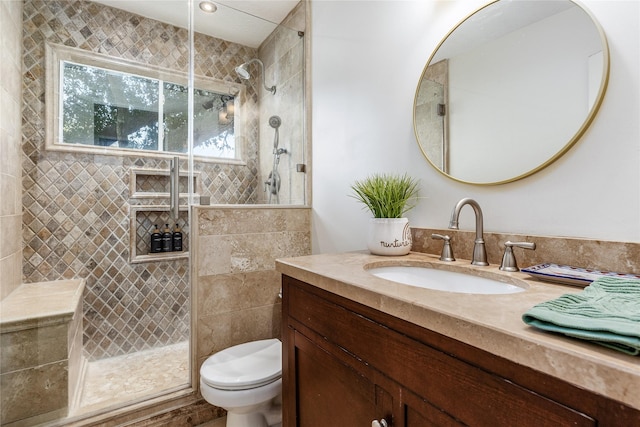 bathroom with a tile shower, vanity, and toilet