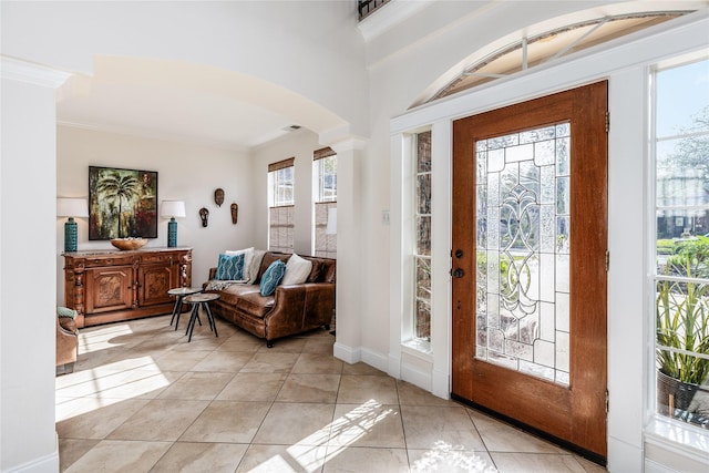 tiled foyer featuring ornamental molding and ornate columns