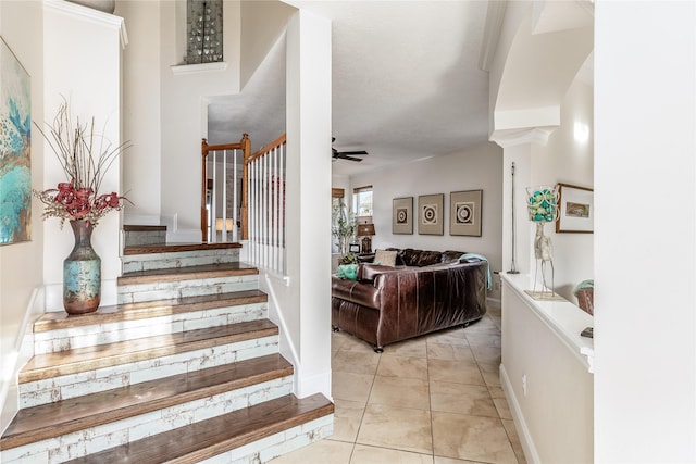 stairs featuring tile patterned floors, ornate columns, and ceiling fan