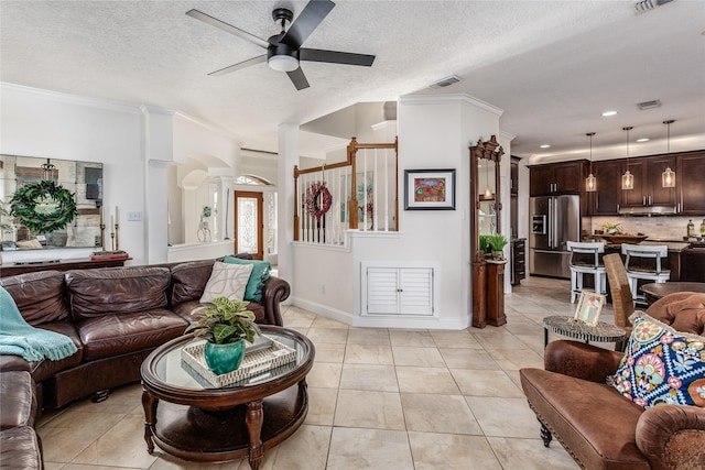 tiled living room with a textured ceiling, ceiling fan, and ornamental molding