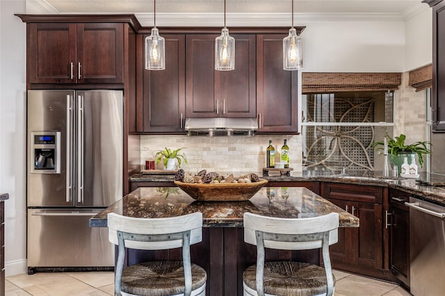 kitchen featuring sink, stainless steel appliances, dark stone countertops, a breakfast bar area, and decorative backsplash