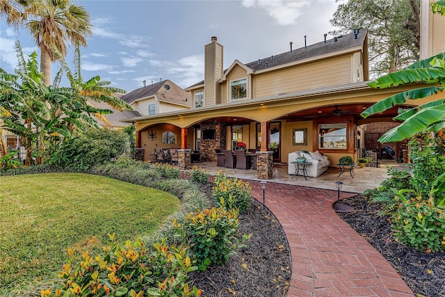 back of house featuring a lawn, outdoor lounge area, ceiling fan, and a patio