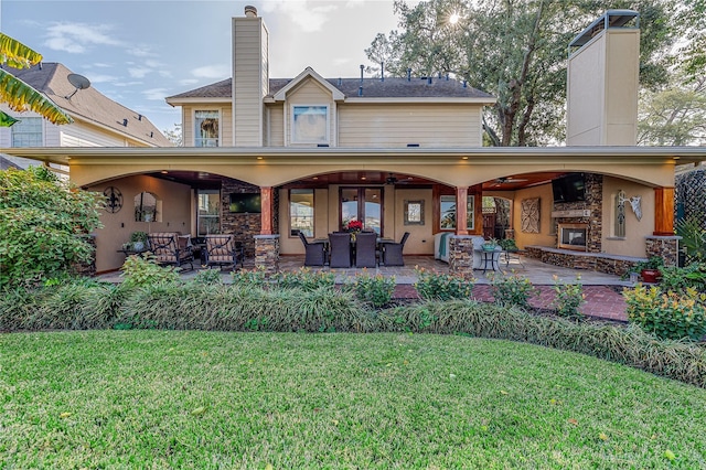 rear view of property featuring a patio area, a yard, and a fireplace