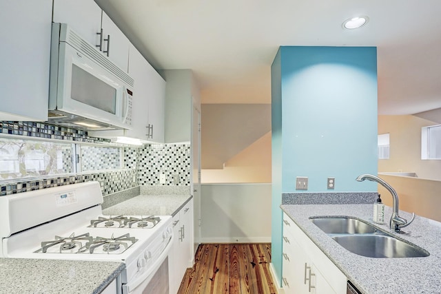 kitchen featuring white appliances, sink, decorative backsplash, light stone countertops, and white cabinetry