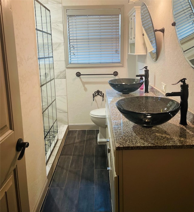 bathroom with toilet, vanity, and a tile shower