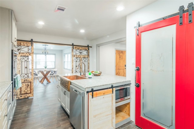 kitchen with visible vents, appliances with stainless steel finishes, a barn door, and a sink