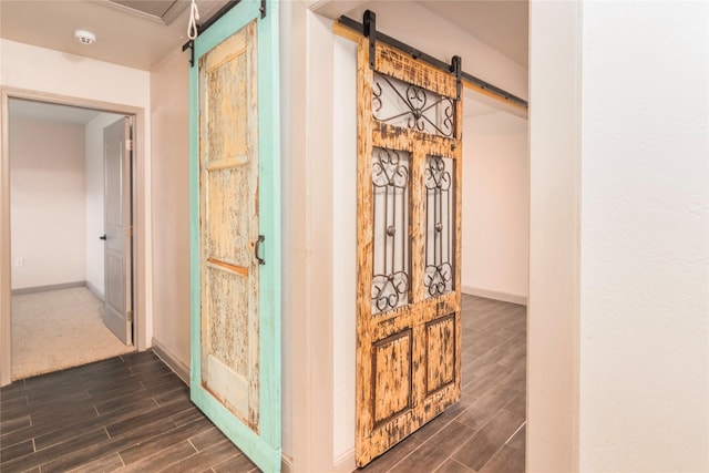 hall featuring wood finish floors, baseboards, and a barn door