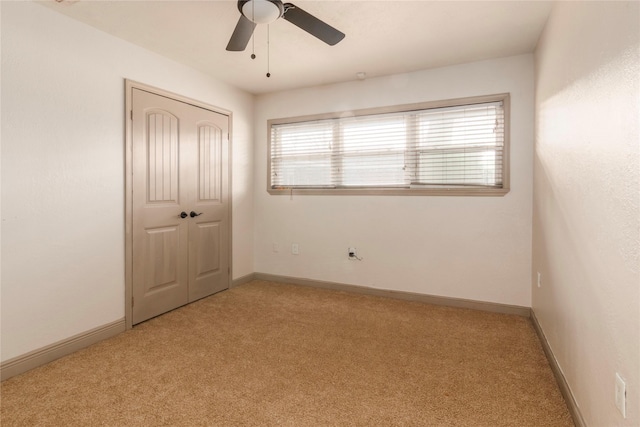 unfurnished room with a ceiling fan, light colored carpet, and baseboards