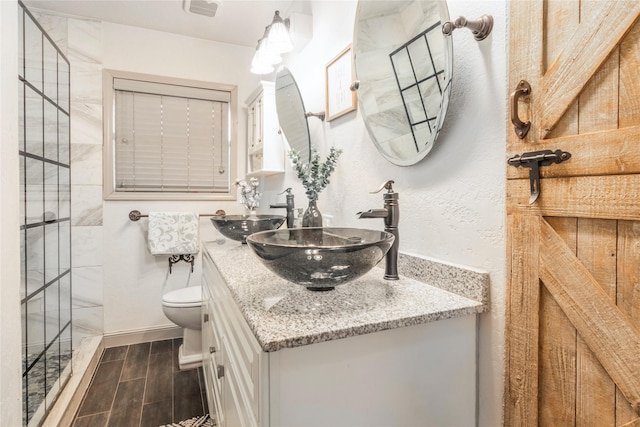 bathroom featuring wood tiled floor, toilet, double vanity, and a sink