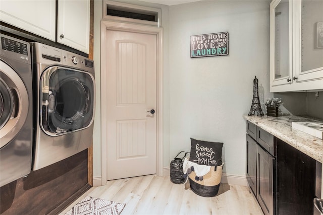 laundry area featuring cabinet space, washer and dryer, light wood-style flooring, and baseboards