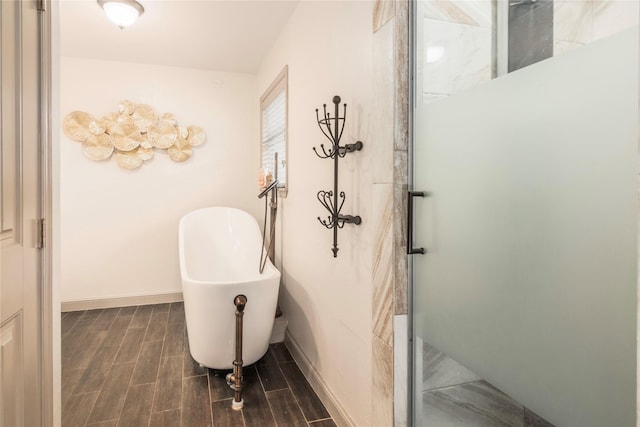 bathroom featuring a shower stall, a freestanding bath, baseboards, and wood tiled floor