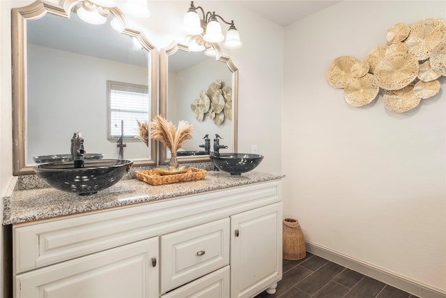 full bath with double vanity, wood tiled floor, baseboards, and a sink