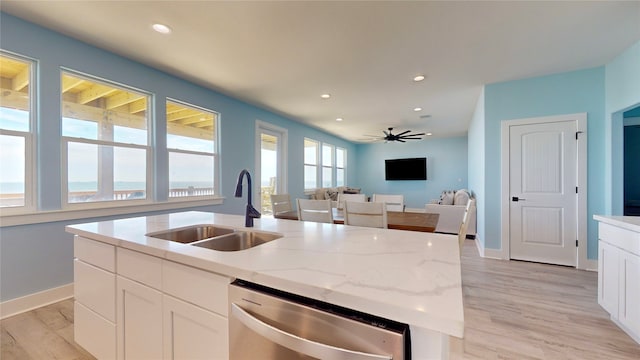 kitchen featuring sink, stainless steel dishwasher, ceiling fan, an island with sink, and white cabinetry