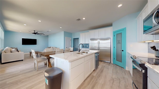 kitchen featuring a center island with sink, white cabinets, stainless steel appliances, and sink