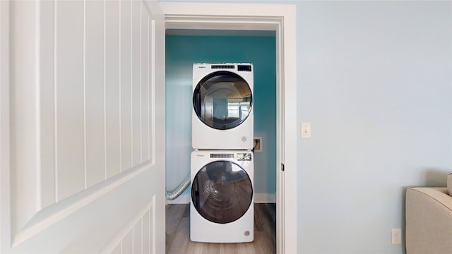 clothes washing area featuring stacked washing maching and dryer and hardwood / wood-style flooring