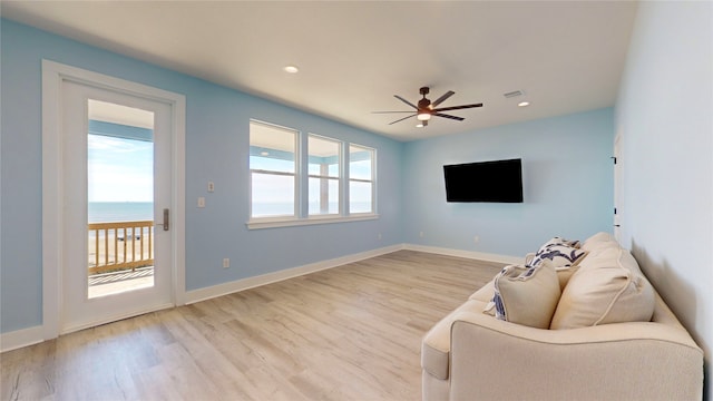 unfurnished room with ceiling fan, a water view, and light hardwood / wood-style flooring