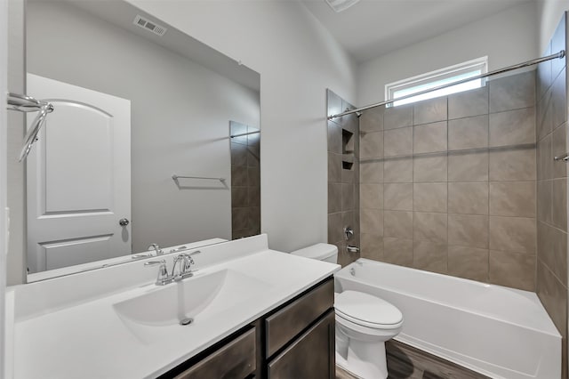 full bathroom with hardwood / wood-style floors, vanity, toilet, and tiled shower / bath