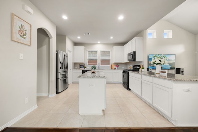 kitchen featuring backsplash, light stone counters, a kitchen island, black appliances, and white cabinetry