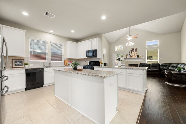 kitchen with a center island, lofted ceiling, black appliances, white cabinets, and sink