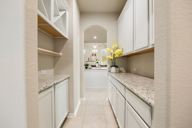 bar with light stone counters, white cabinets, and light tile patterned flooring